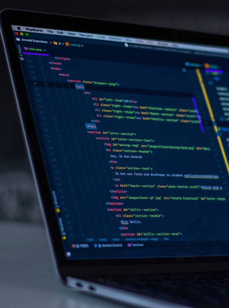 A laptop on a dark desk showing a code editor with a project open.